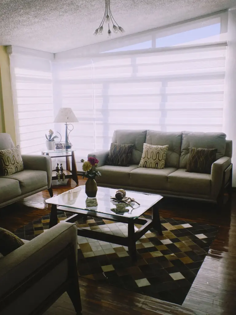 Day and night roller blinds across a living room bay window